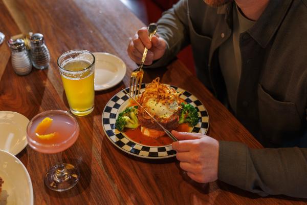 Close-up of a man enjoying a meatloaf entree with mashed potatoes, broccoli, and drinks at a Cap City Fine Diner in Dublin, Ohio.