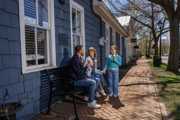Family enjoying ice cream on a sunny day while sitting on a bench along a brick sidewalk in Historic Dublin, Ohio.