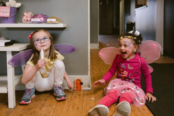 Two little girls dressed in fairy wings finding the fairy door in Winans on the Fairy Door Trail