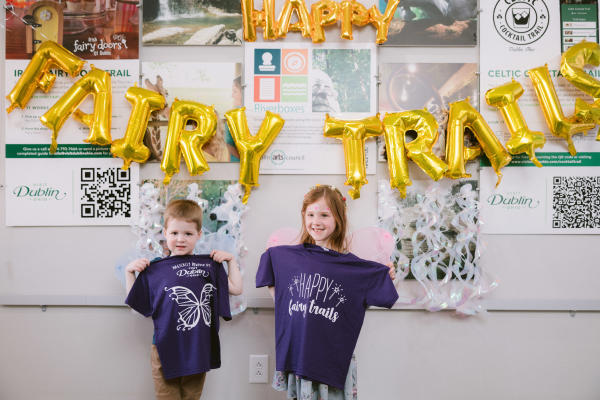 A young boy and girl holding their Fairy Door Trial t-shirts