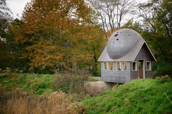 Watch House public art installation surrounded by trees and grass in fall color.