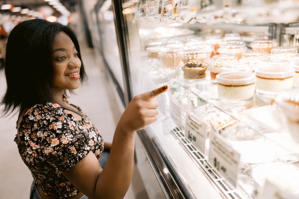 Young girl pointing through the glass at colorful desserts