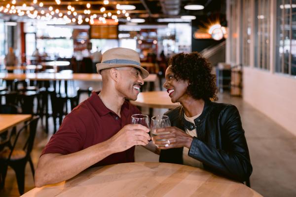 A couple cheersing wine glasses in front of Market Bar at North Market Bridge Park