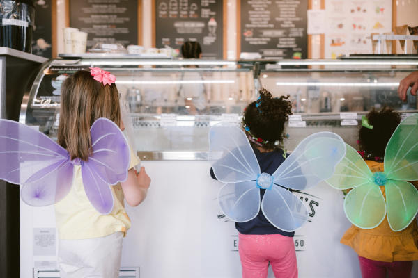 Three little girls with colorful fairy wings on the Fairy Door Trial looking through the glass at ice cream in Johnson's Real Ice Cream