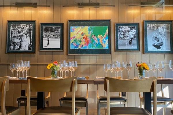 Sophisticated private dining room at Shawnee Station, featuring modern wood paneling, framed golf art, and elegant table settings with wine glasses.