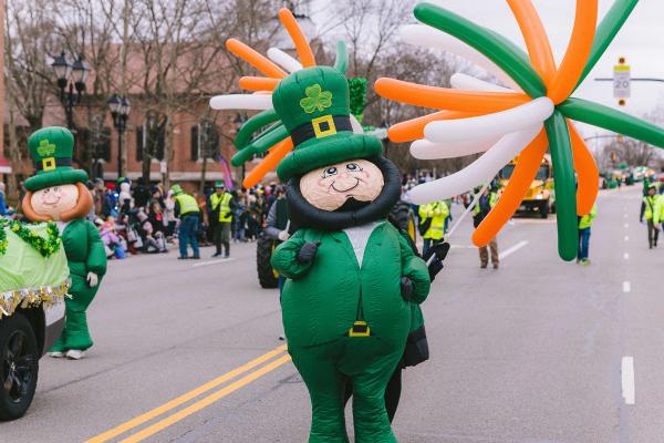 A blow up leprechaun walking along green and orange balloons in the Dublin St. Patrick's Day Parade