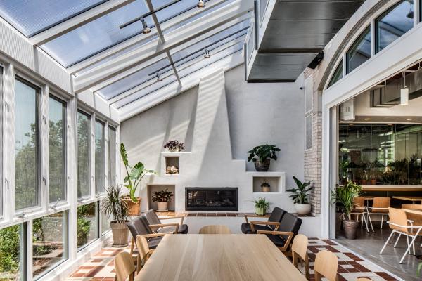 Getaway Brewing's private room with a bright, airy indoor garden with a glass roof, plants, a fireplace, and a wooden table with chairs.