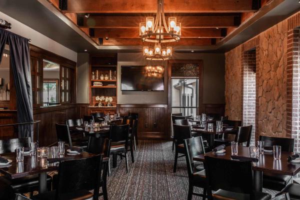 Elegant private dining room at Mezzo with warm wood accents, stone walls, chandeliers, and intimate table settings for special events.