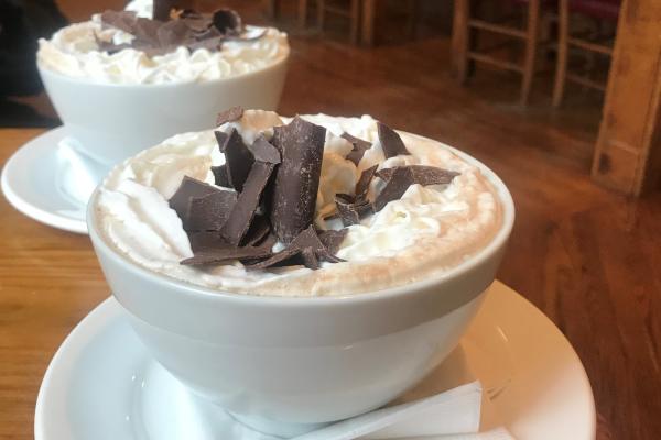 Giants bowls of hot chocolate topped with whipped cream and chocolate shavings