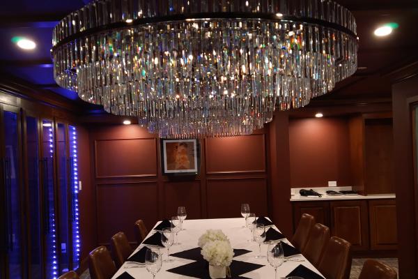 Tucci's elegant private dining room with a long table, set with glassware and black napkins, beneath a large crystal chandelier.