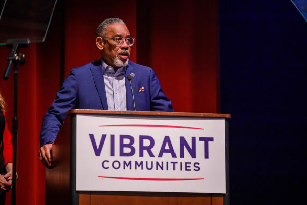 Arvis Dawson stands behind a podium that has a sign that says Vibrant Communities