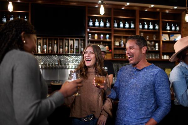 Friends laughing and enjoying drinks together inside a lively local bar, highlighting Fayetteville’s nightlife and social scene.