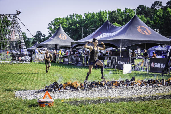 Participant jumping over fire during an outdoor obstacle race event in the Fayetteville, NC area