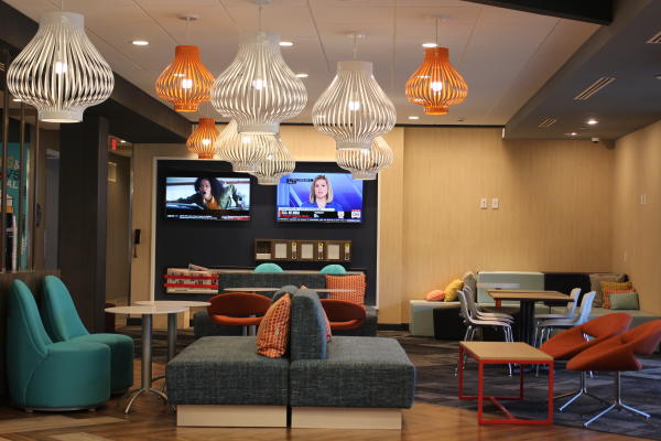 Colorful lounge area at Tru by Hilton in Fayetteville, NC, featuring modern light fixtures, cozy seating with bright pillows, and a relaxed, contemporary vibe—perfect for unwinding after a self-care weekend.