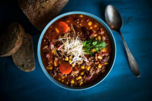 generic bowl of chili in a blue bowl with a spoon next to the bowl on the blue table
