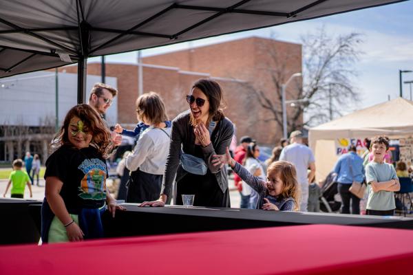 A mother laughs as a child tosses an item during a mini game at the Bakery District Street Fest in Fort Smith, Arkansas