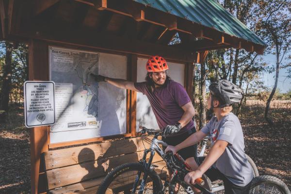 A father and son on bikes look at the trail map at Ben Geren park in Fort Smith, Arkansas.