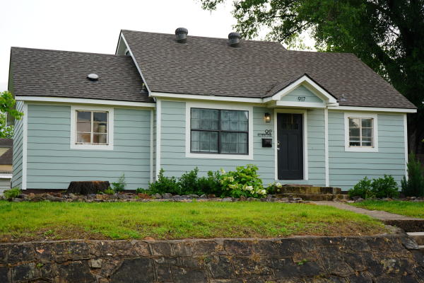 A modern cottage Airbnb rental painted in baby blue sits under an overcast sky in Fort Smith, Arkansas.
