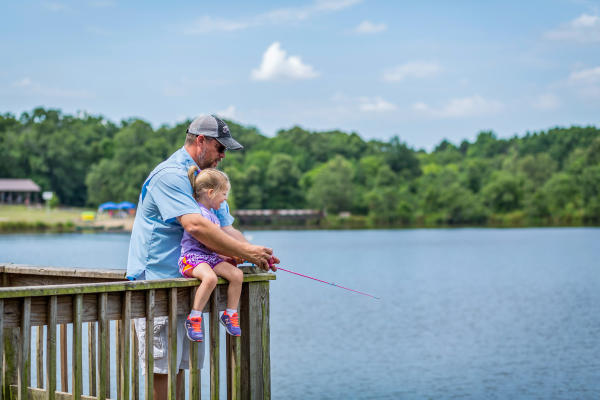 A dad teaches his young daughter to fish at Wells Lake in Fort Smith.