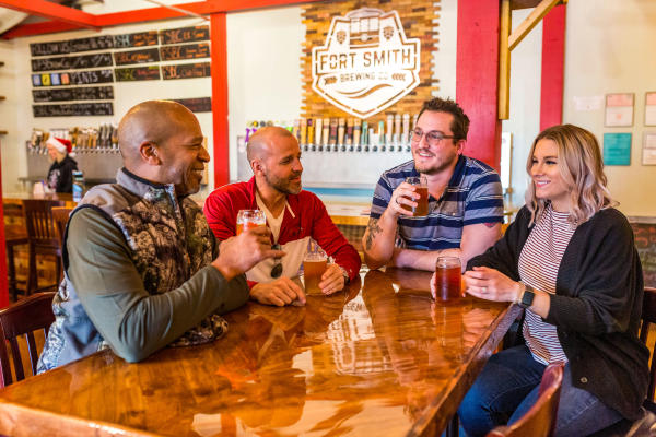 A group of 4 friends enjoy beverages together at Fort Smith Brewing Company.