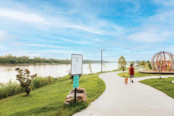 A man walks with his dog on Greg Smith River Trail in Fort Smith.