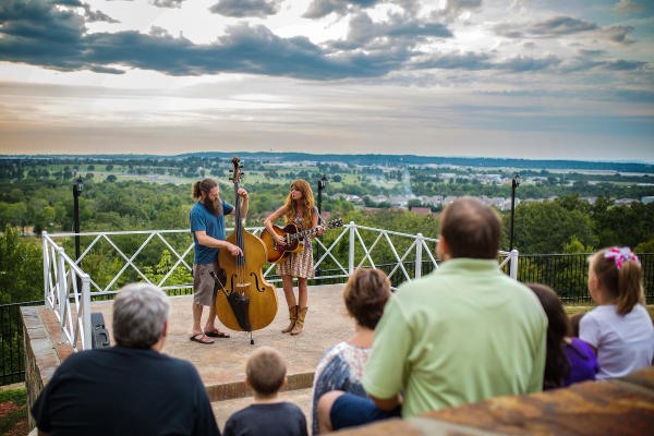 A man with a classical upright bass and a woman with an acoustic guitar play to a crowd at the scenic McClure Amphitheater in Fort Smith, Arkansas.