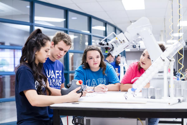A group of four students interact with a robotic arm during a robotics lab at University of Arkansas—Fort Smith.