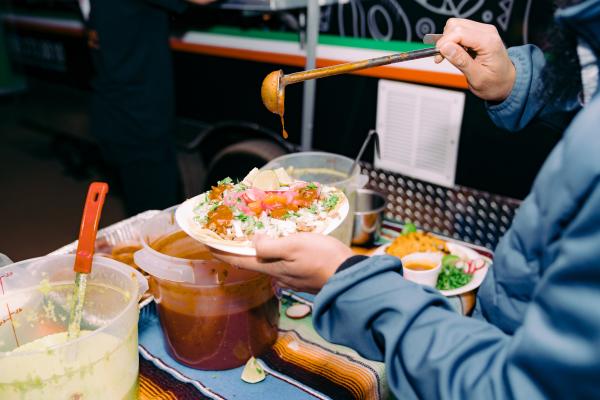 Person drizzles salsa over taco plate