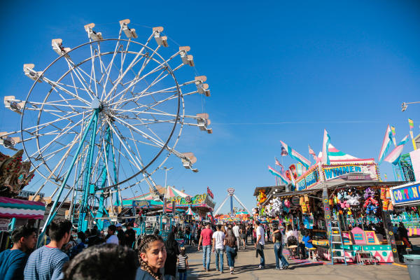 People wait in line to ride swings and Ferris wheel