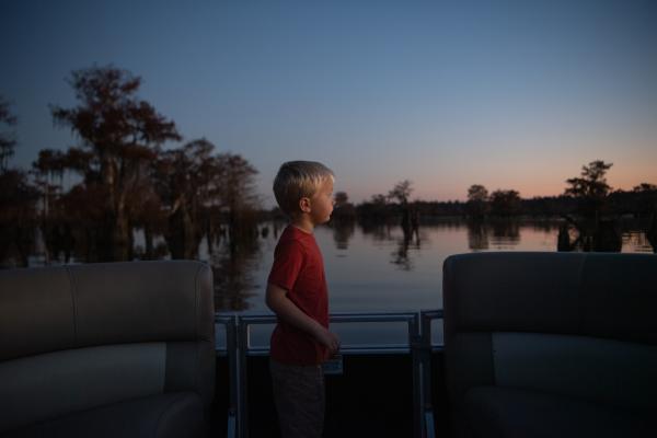 Boy watching sunrise while on boat at Dead Lakes