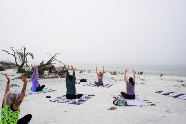 women practicing yoga on the beach