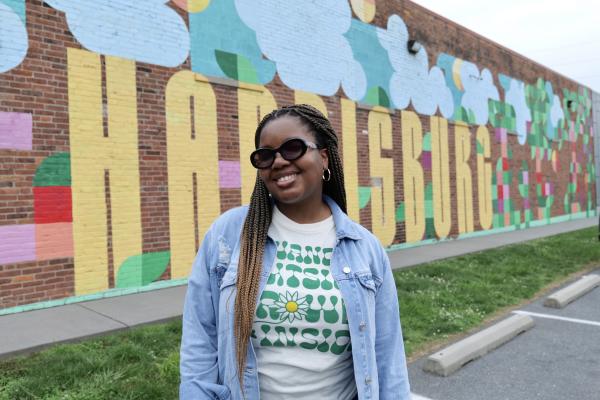 A woman in front of the Harrisburg mural.