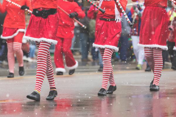 People in red coats and candy can tights marching in the Holiday Parade