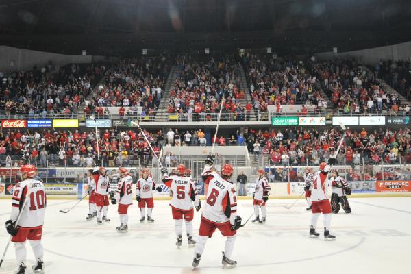 Huntsville Havoc hockey game with fans in red and white cheering from stadium stands.
