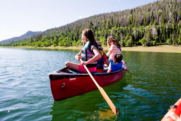 Family in a red canoe on the water of Navajo Lake, Utah.