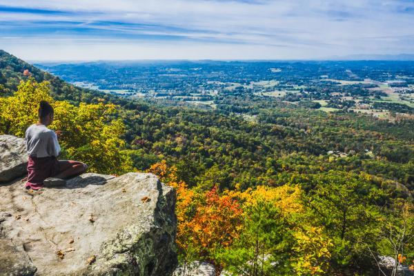 A woman sits on a rock outcropping on House Mountain in fall
