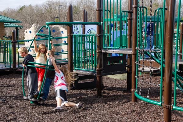 Children at McFee Park laugh as they enjoy the playground equipment.