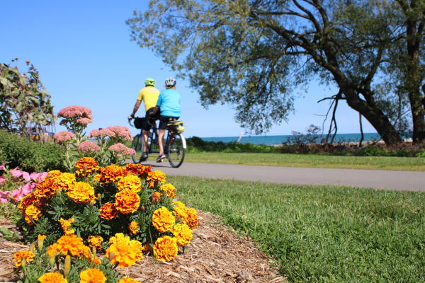 Mariner's Trail couple on tandem bike with orange flowers in foreground