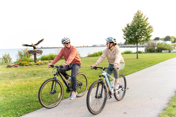 two bikers on Mariners Trail with eagle sculpture in background