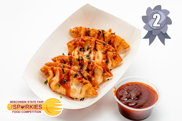 A tray of six golden-brown fried dumplings drizzled with red sauce and garnished with chopped herbs, served with a cup of dipping sauce on the side. A silver ribbon with the number 2 indicates second place in the Wisconsin State Fair’s Sporkies Food Competition, marked by the Sporkies logo in the bottom left corner.