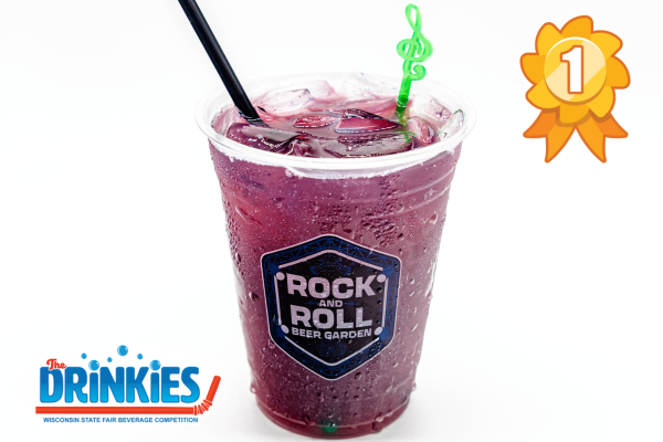 A clear plastic cup filled with a purple iced beverage, garnished with a curly green straw and a black stirrer. The cup is labeled with a “Rock and Roll Beer Garden” sticker. An orange and yellow first-place ribbon graphic is displayed in the top right corner, and the Drinkies Wisconsin State Fair Beverage Competition logo appears in the bottom left corner.