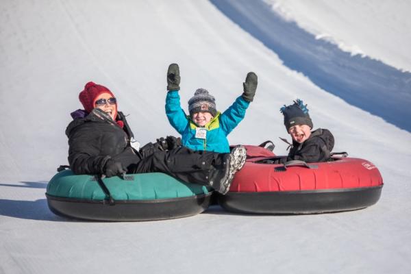 Family tubing down a snowy hill