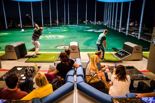 Young people swinging golf clubs at Topgolf