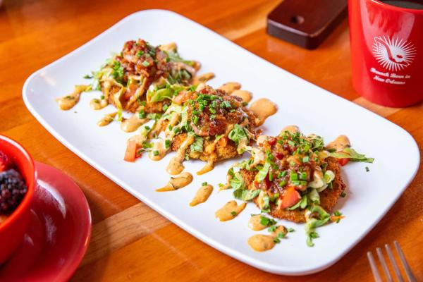 Three fried green tomatoes with garnishes are served on a rectangle white plate