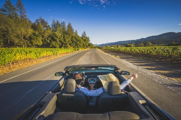 Visitors enjoy the sunshine and fresh air in their convertible on a drive through Napa Valley.