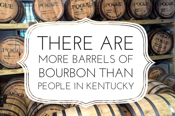 Bourbon barrels with a white sign that reads there are more barrels of bourbon than people in Kentucky.