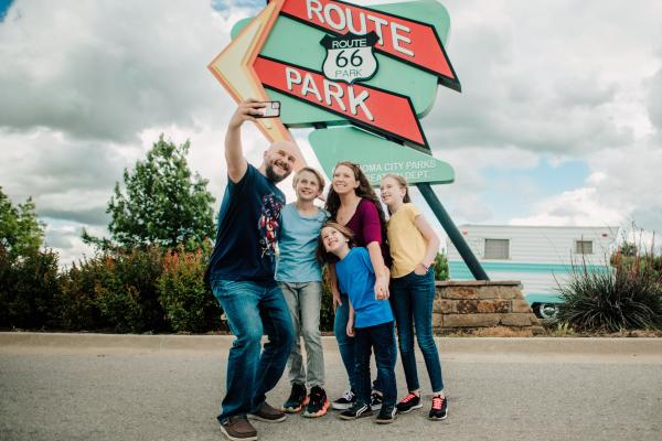 A family poses for a selfie in front of the Route 66 Park sign