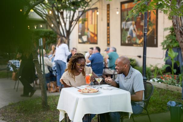 A man and woman are dining at Max's Brick Oven in Paducah, surrounded by people as they enjoy their meal and drinks.