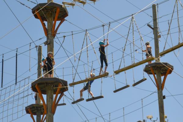 Multiple kids attempting to cross a ropes course