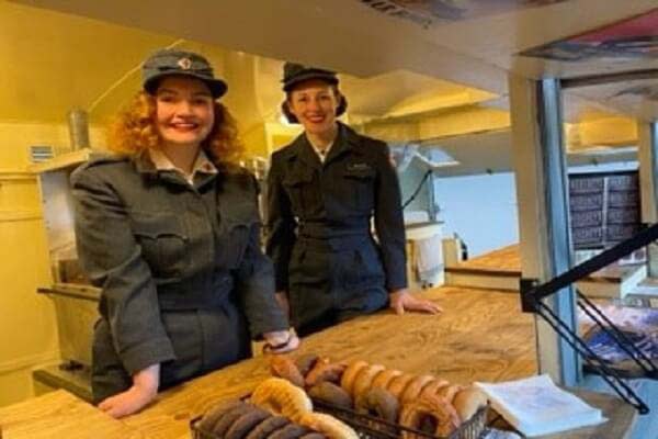 two women dressed in World War Military attire selling Donuts